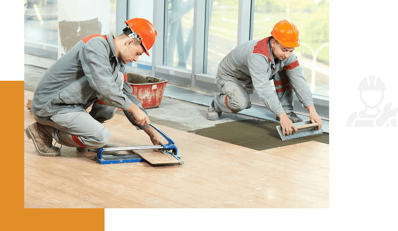 Two men in hard hats working on a floor.