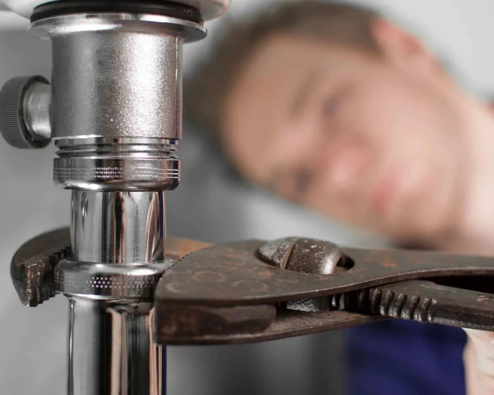 A man is sleeping behind the pipes of a faucet.