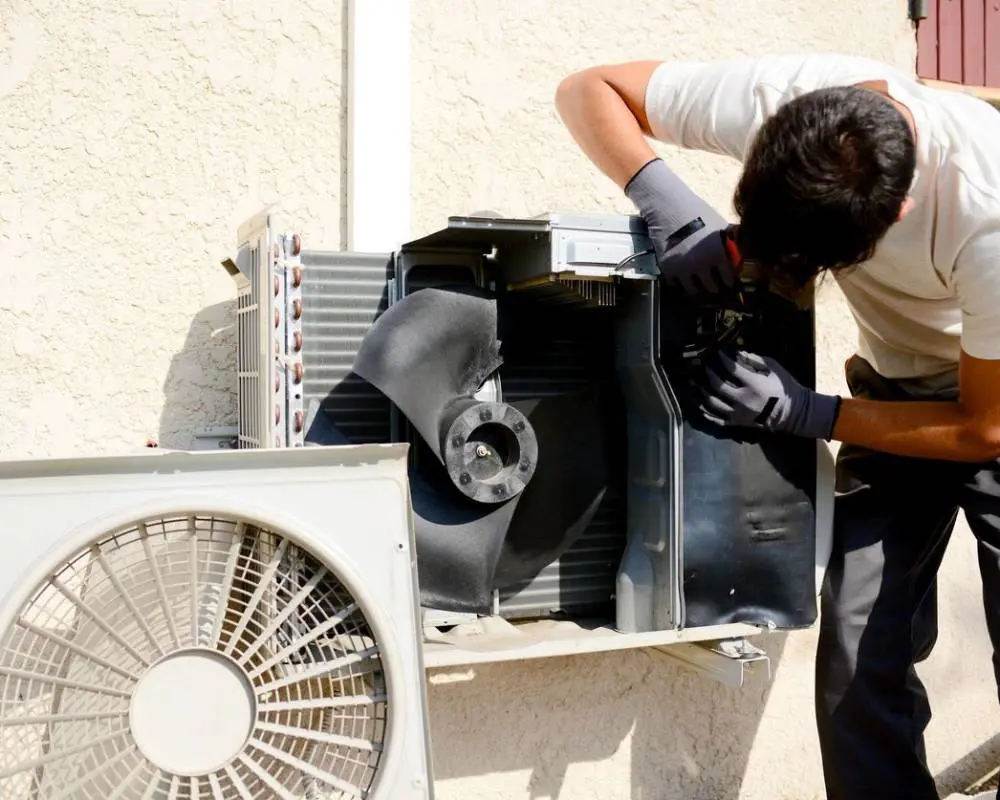 A man working on an air conditioner outside.